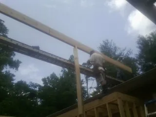 Carpenter setting a ridge beam over a new addition frame — Ice Dam Removal by Roofing Brothers in Kenly