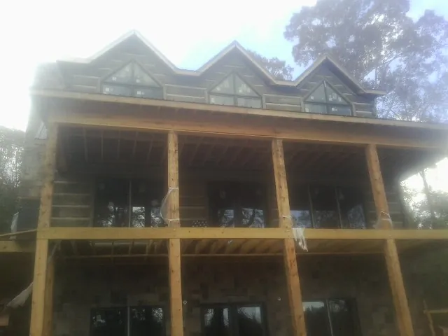 Dormers and porch framing on a large log home under construction — Roof Coating work by our crew in Kenly