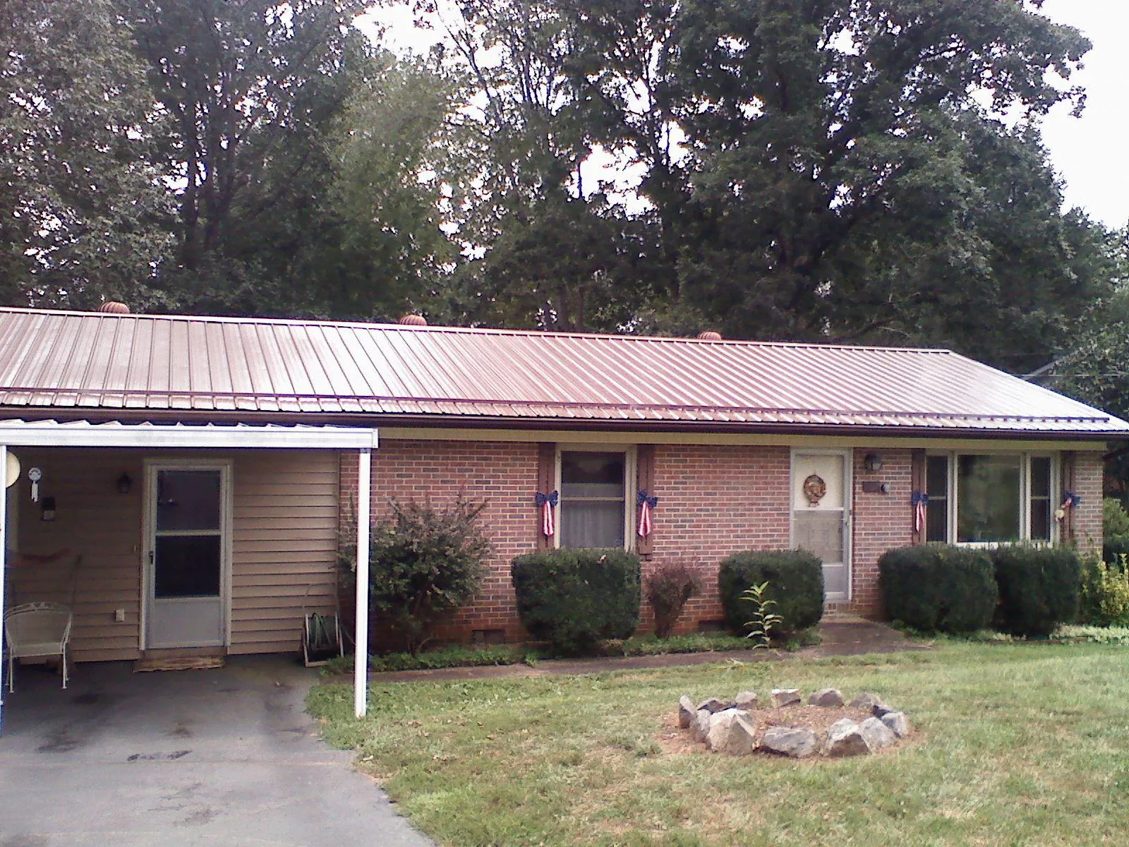 Bronze metal roof and carport on a brick ranch home — Roof Repair work by our crew in Kenly